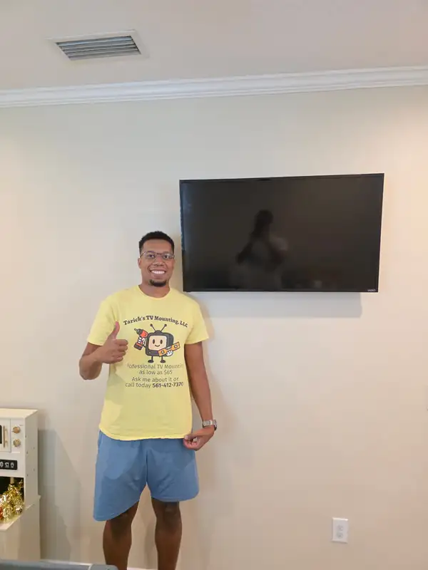 Tarick, owner of Tarick's TV Mounting, giving a thumbs up below a Vizio TV on a full-motion mount in a Melbourne, FL living room