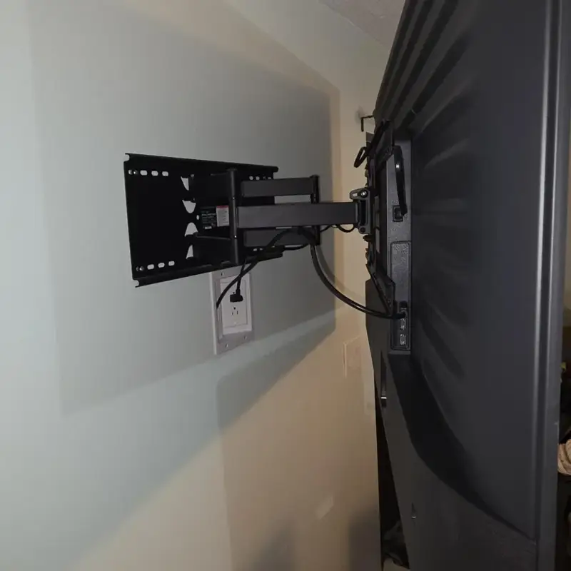 Full-motion TV arm extended from the wall above a recessed in-wall power outlet in Merritt Island, FL