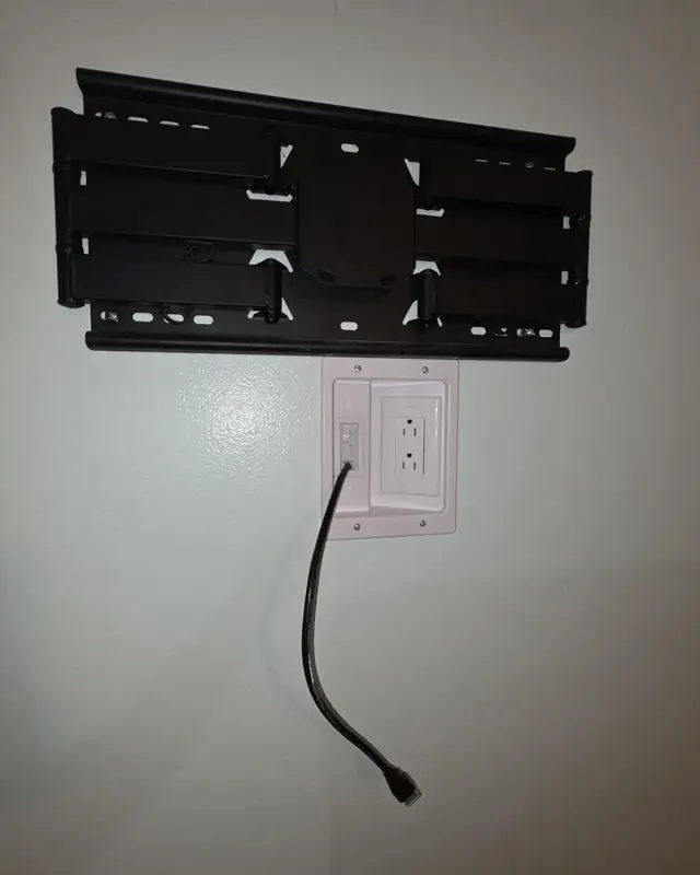 Recessed in-wall power outlet and cable port installed below a full-motion TV mount in Merritt Island, FL