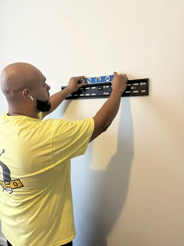 Noel, a Tarick's TV Mounting technician, leveling a TV mount wall plate in Palm Beach Gardens, FL